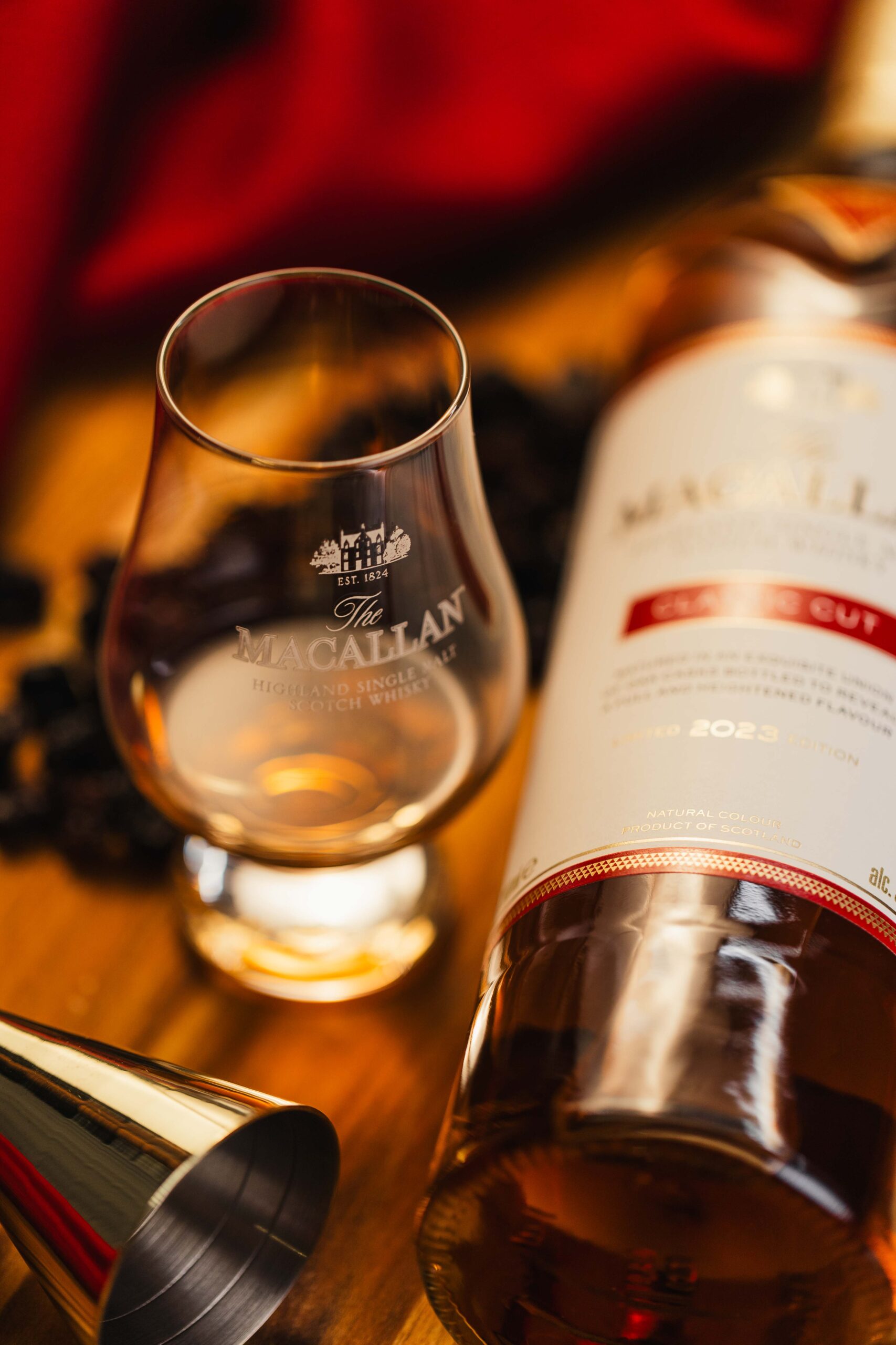 Foto em close-up de uma dose de uísque Single Malt Macallan em um copo de degustação Glencairn, com a garrafa ao fundo, produzida pela Lion Audiovisual.