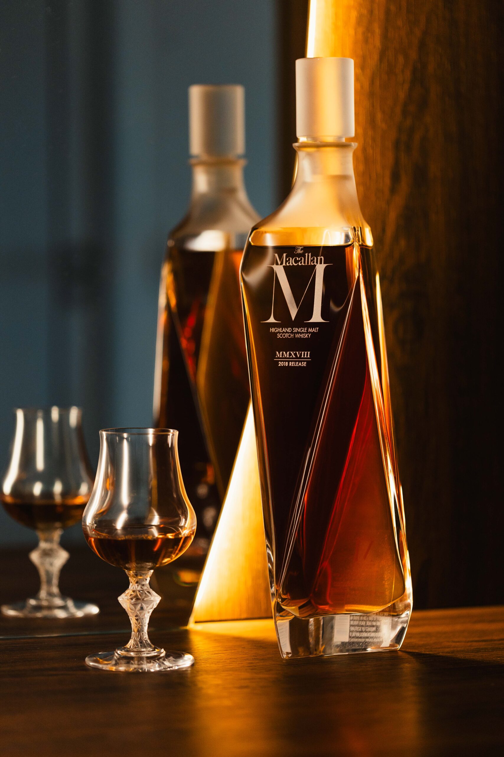 Duas garrafas de licor premium e taças de degustação sobre mesa de madeira com iluminação quente, fotografia por Lion Audiovisual.