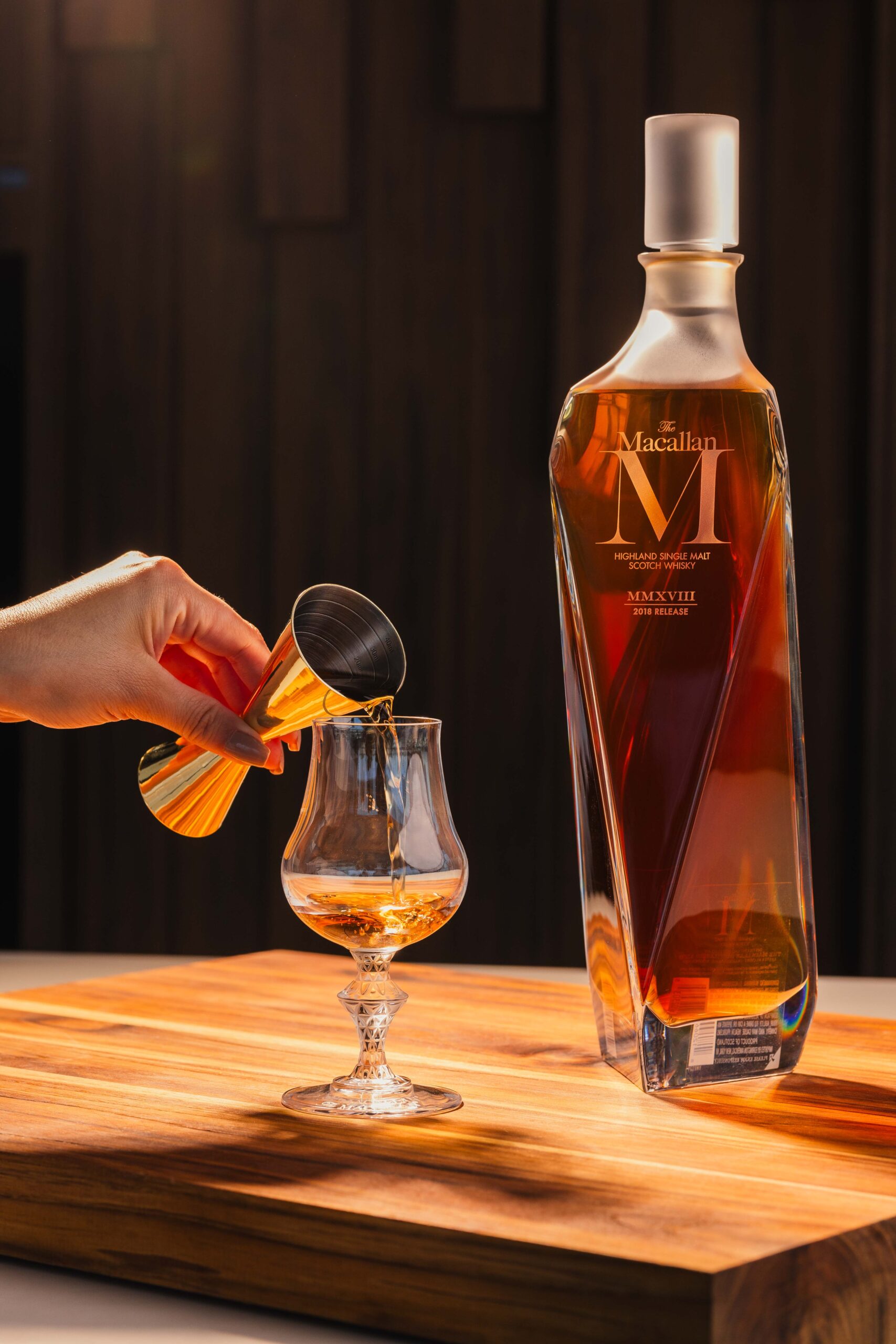 Uma foto de produto profissional em low-key de uma garrafa de The Macallan 12 Sherry Oak Cask, destacando a textura do vidro e a cor dourada, tirada por lion audiovisual e guilherme rossi